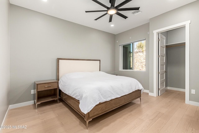 bedroom featuring ceiling fan, a walk in closet, and light wood-type flooring