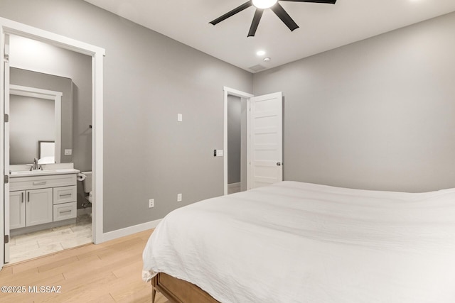 bedroom with ceiling fan, sink, light hardwood / wood-style floors, and ensuite bath