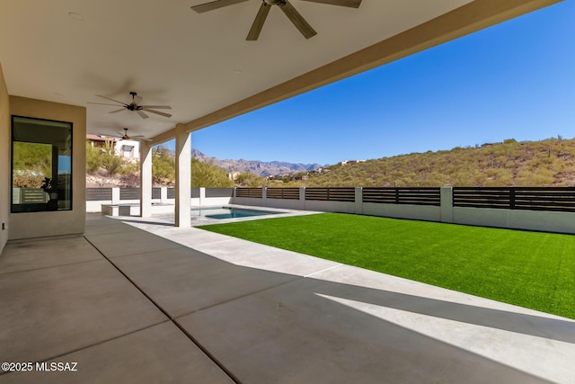 view of patio with a mountain view, a fenced in pool, and ceiling fan