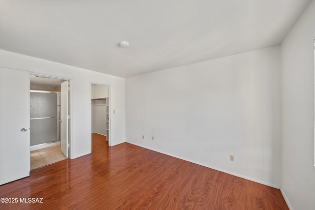 unfurnished bedroom with a spacious closet, hardwood / wood-style floors, and a closet