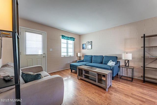 living room featuring brick wall and light hardwood / wood-style floors