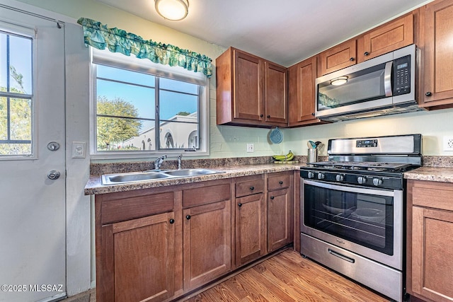 kitchen with sink, appliances with stainless steel finishes, and light hardwood / wood-style floors