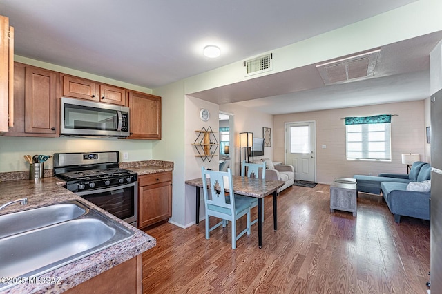 kitchen with appliances with stainless steel finishes, sink, and dark wood-type flooring