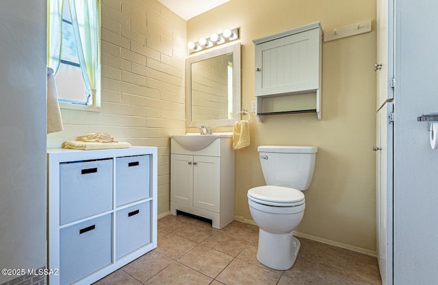 bathroom with toilet, tile patterned floors, brick wall, and vanity