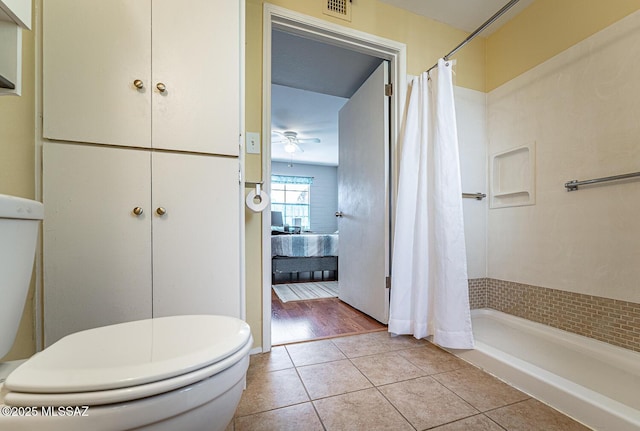 bathroom with a shower with shower curtain, ceiling fan, toilet, and tile patterned floors