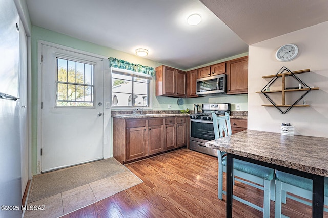 kitchen with sink, appliances with stainless steel finishes, and hardwood / wood-style floors