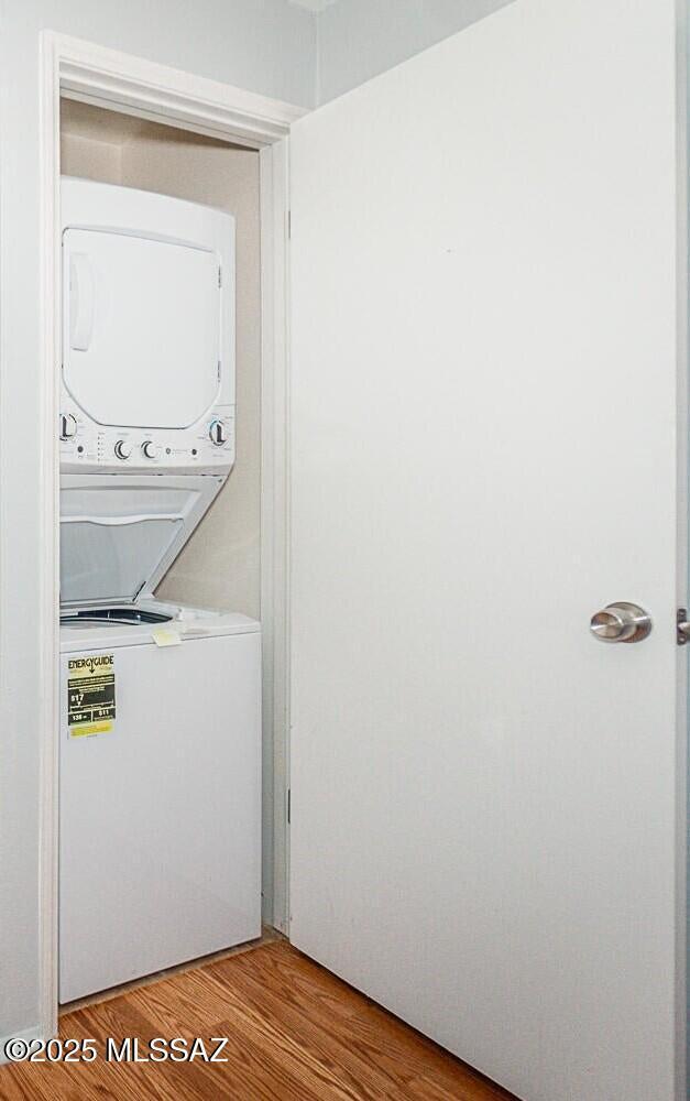 laundry area with stacked washing maching and dryer and light hardwood / wood-style floors