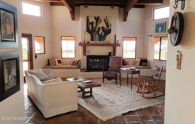 living room featuring beamed ceiling, a large fireplace, and a high ceiling