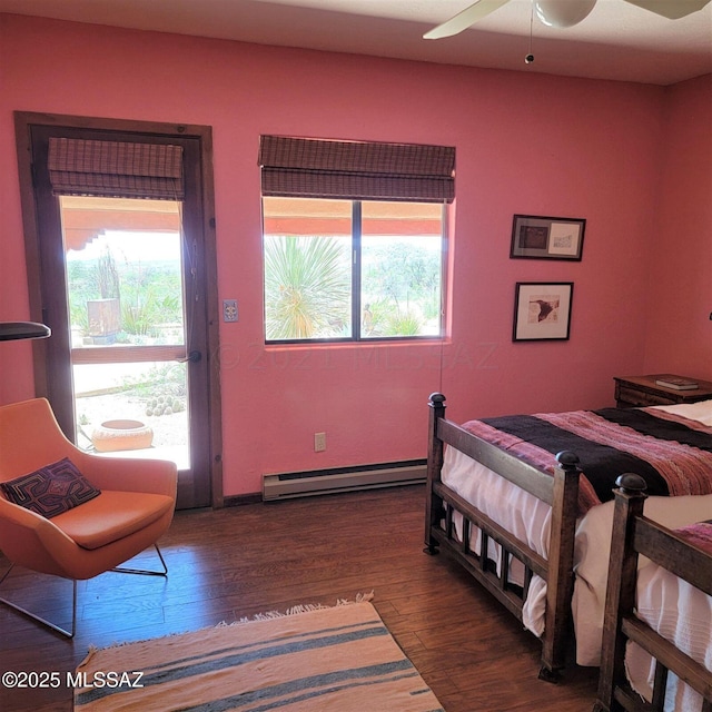 bedroom with multiple windows, a baseboard heating unit, dark wood-type flooring, and ceiling fan