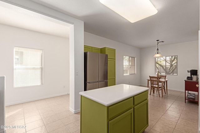 kitchen with a center island, light tile patterned floors, stainless steel refrigerator, and decorative light fixtures