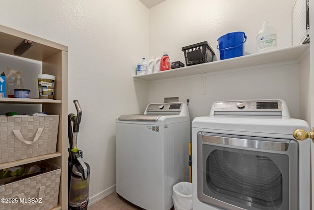 clothes washing area with washer and clothes dryer and tile patterned floors