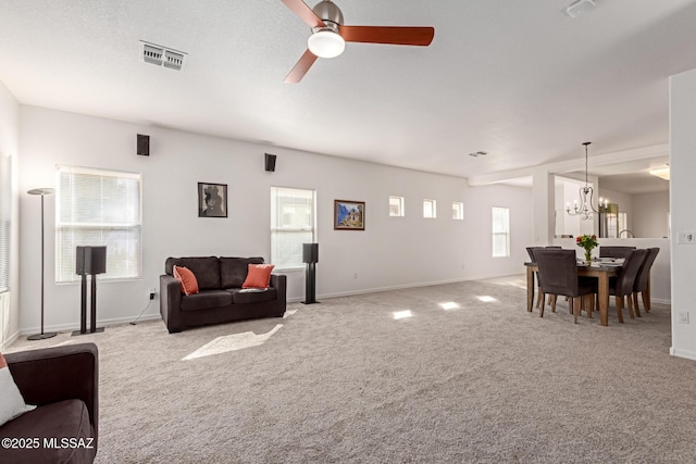 living room with carpet flooring and ceiling fan with notable chandelier