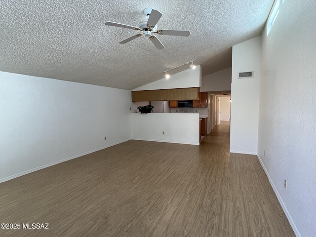 kitchen featuring white appliances, vaulted ceiling, light hardwood / wood-style floors, and a textured ceiling