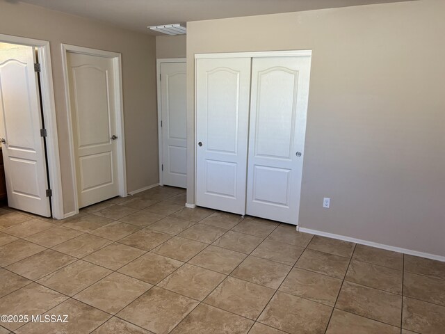 unfurnished bedroom with connected bathroom, a spacious closet, a closet, and light tile patterned flooring