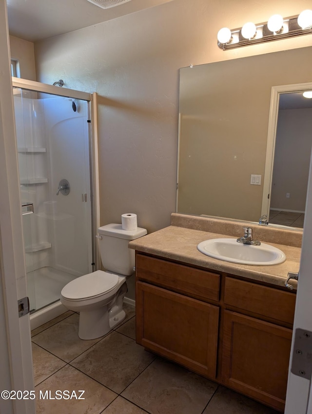 bathroom featuring tile patterned flooring, vanity, toilet, and walk in shower