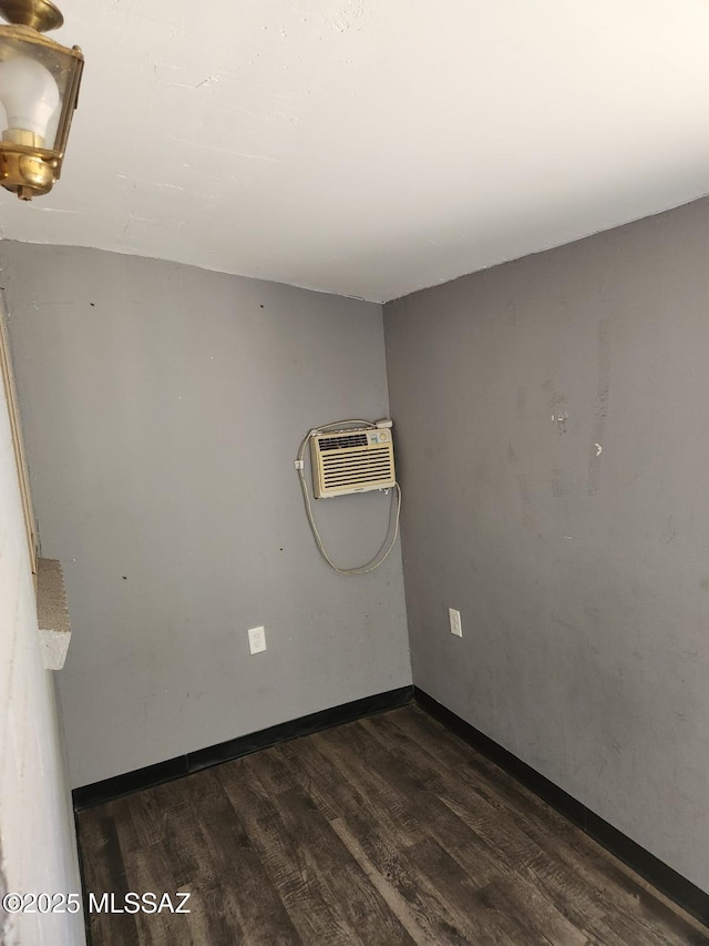 spare room with an AC wall unit and dark wood-type flooring