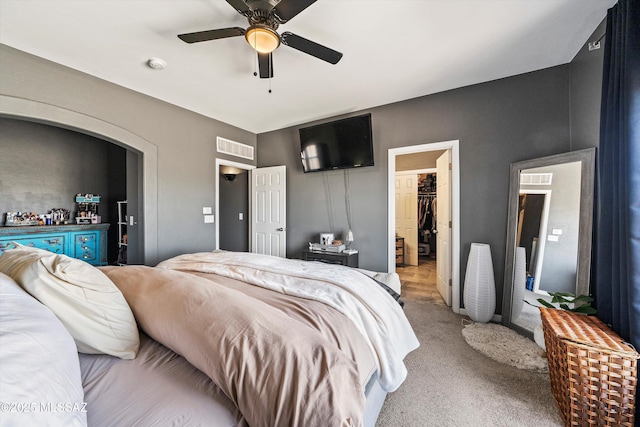 bedroom featuring ceiling fan, a spacious closet, light colored carpet, and a closet