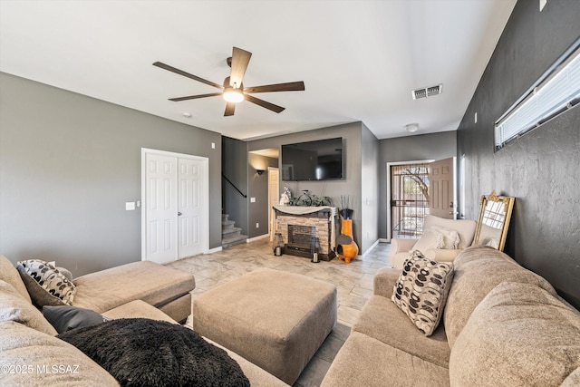 living room with ceiling fan and a fireplace