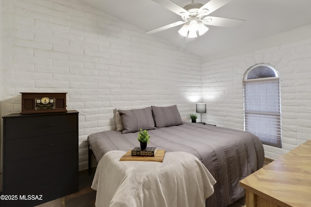 bedroom with vaulted ceiling, ceiling fan, and brick wall