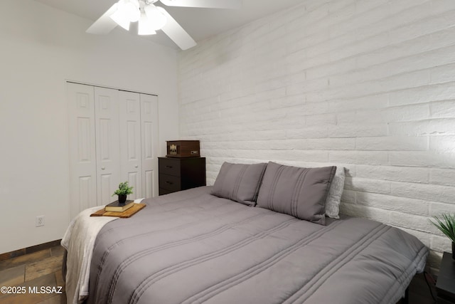 bedroom with brick wall, ceiling fan, and a closet