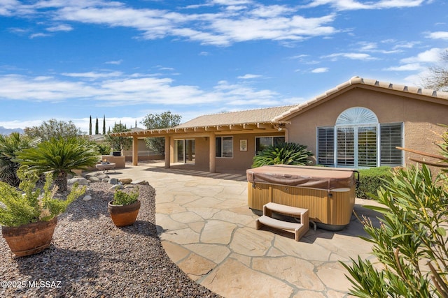 rear view of house with a hot tub and a patio area