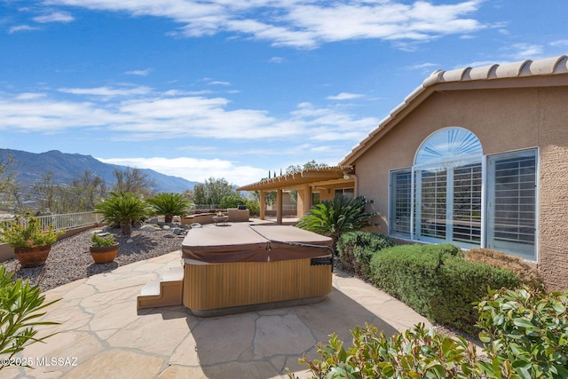 view of patio / terrace featuring a hot tub and a mountain view