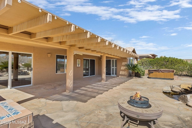 view of patio / terrace with a hot tub and a fire pit