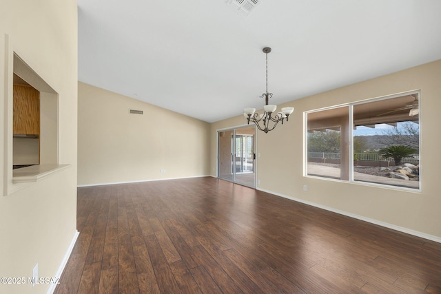 empty room featuring an inviting chandelier, dark wood-type flooring, and vaulted ceiling