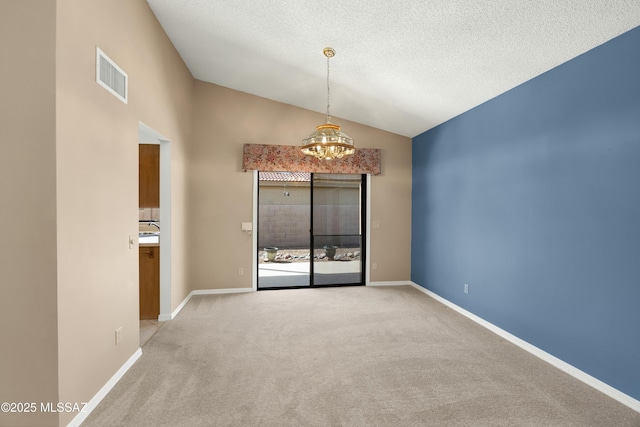 carpeted empty room with vaulted ceiling, an inviting chandelier, and a textured ceiling