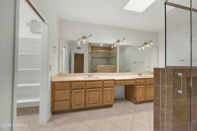 bathroom featuring tile patterned flooring, vanity, a skylight, and a shower with shower door