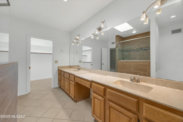 bathroom featuring vanity, tile patterned flooring, a skylight, and walk in shower