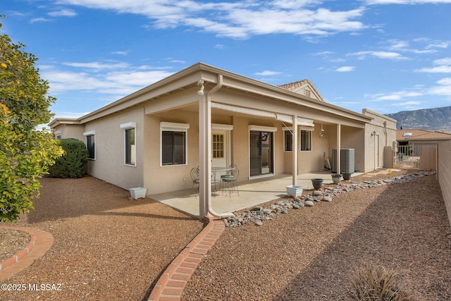 rear view of property featuring cooling unit, a mountain view, and a patio