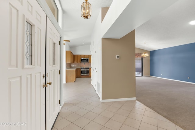 carpeted foyer featuring lofted ceiling, a textured ceiling, and an inviting chandelier