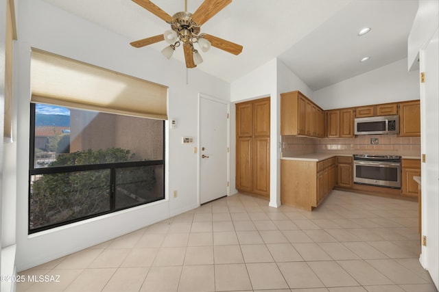 kitchen featuring tasteful backsplash, lofted ceiling, stainless steel appliances, and light tile patterned floors