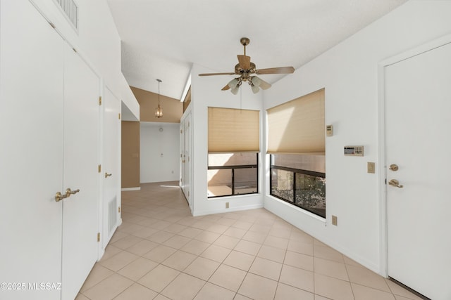 empty room with light tile patterned floors, vaulted ceiling, and ceiling fan