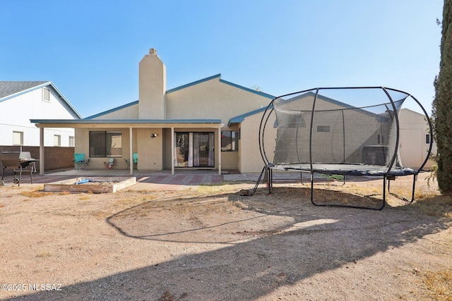 2780 W Camino Llano, Tucson, AZ 85742 - rear view of house with a patio, stucco siding, a trampoline, and a chimney