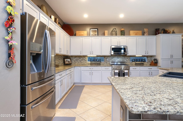 kitchen featuring white cabinetry, appliances with stainless steel finishes, light tile patterned floors, and light stone counters