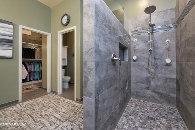 bathroom featuring tiled shower, toilet, and tile patterned flooring