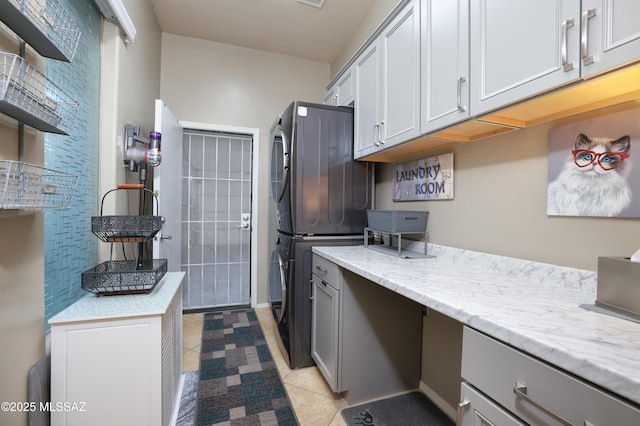 kitchen with gray cabinetry, light tile patterned floors, light stone counters, and stainless steel refrigerator