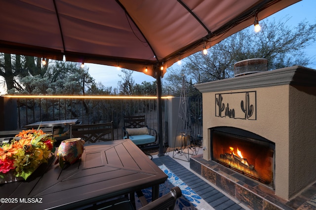 patio terrace at dusk with an outdoor fireplace and a gazebo