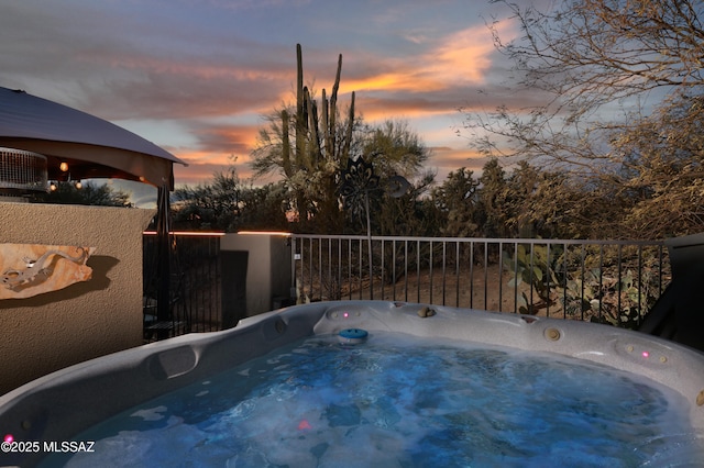 pool at dusk with a hot tub and central AC unit