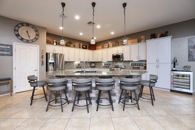 kitchen with a large island, sink, light tile patterned floors, appliances with stainless steel finishes, and white cabinets