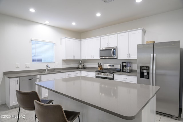 kitchen with appliances with stainless steel finishes, sink, white cabinets, and a kitchen breakfast bar