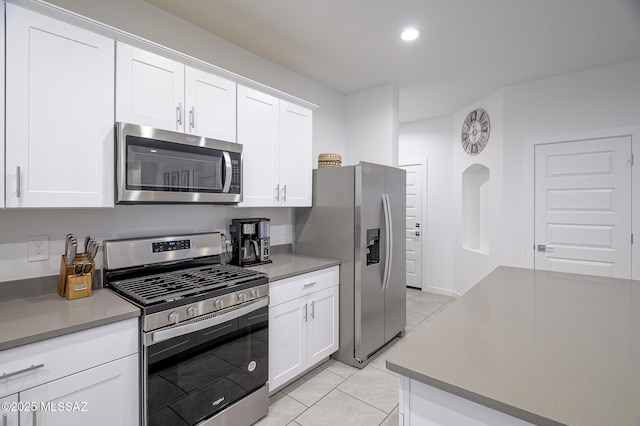 kitchen with stainless steel appliances, white cabinetry, and light tile patterned flooring