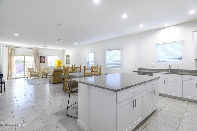 kitchen featuring sink, a breakfast bar area, white cabinets, a center island, and light tile patterned floors