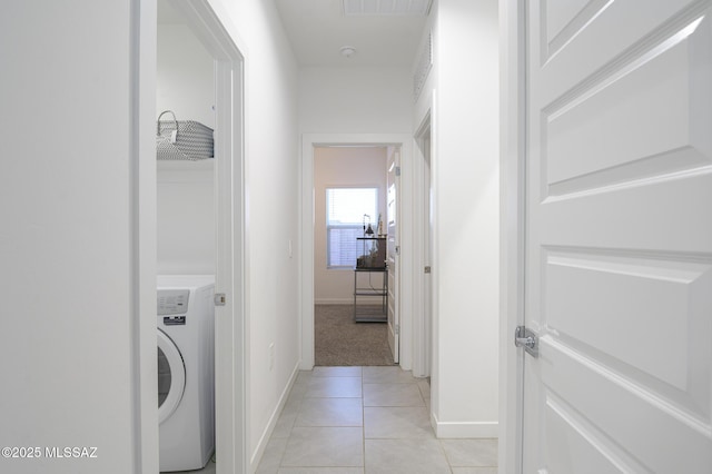 hallway with washer / dryer and light tile patterned flooring