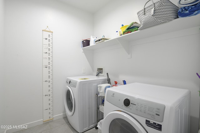 clothes washing area featuring light tile patterned flooring and washer and clothes dryer