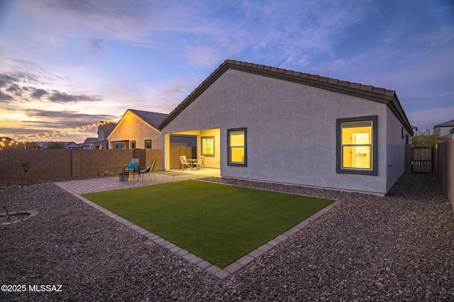 back house at dusk with a patio area