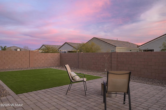 patio terrace at dusk featuring a yard