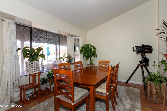 tiled dining area featuring lofted ceiling